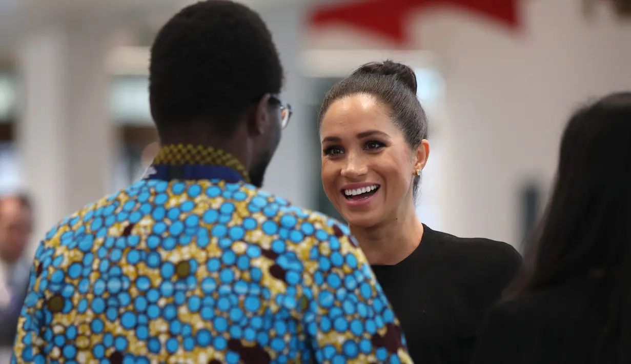 Duchess of Sussex, Meghan Markle berbincang dengan seorang siswa saat mengunjungi Association of Commonwealth Universities (ACU) di London, Kamis (31/1). Di usia kehamilan 6 bulan, Meghan Markle muncul dengan gaya rambut baru. (Yui MOK/POOL/AFP)