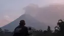 Seorang pria menyaksikan Gunung Merapi menyemburkan material vulkanik ke udara di Sleman, DI Yogyakarta, Selasa (3/3/2020). Gunung Merapi meletus pada pukul 05.22 WIB dengan tinggi kolom 6.000 meter , status waspada (level II). (AP Photo/Slamet Riyadi)