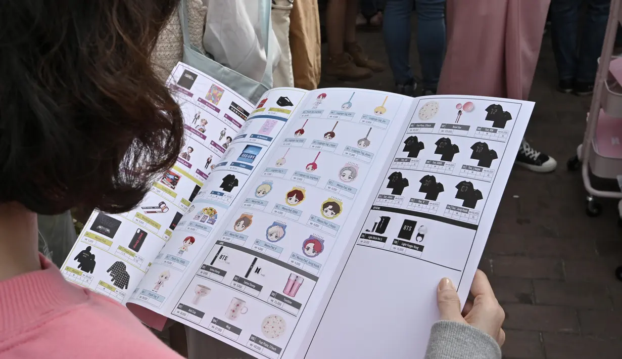 Penggemar melihat brosur sambil mengantre untuk membeli barang-barang BTS dalam toko pop-up BTS di Distrik Gangnam, Seoul, Korea Selatan, Jumat (18/10/2019). Dalam House of BTS Anda akan dimanjakan dengan ratusan merchandise, makanan dan minuman bertema BTS. (Jung Yeon-je/AFP)