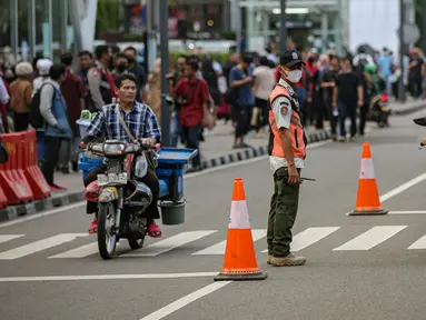 Personel gabungan dari unsur polisi hingga Satpol PP mengatur lalu lintas di kawasan zebra cross Dukuh Atas, Jakarta, Rabu (27/7/2022). Mereka dikerahkan untuk memantau kegiatan peragaan busana Citayam Fashion Week (CFW) guna meminimalisir terjadinya kriminalitas, kemacetan, hingga parkir liar. (Liputan6.com/Faizal Fanani)