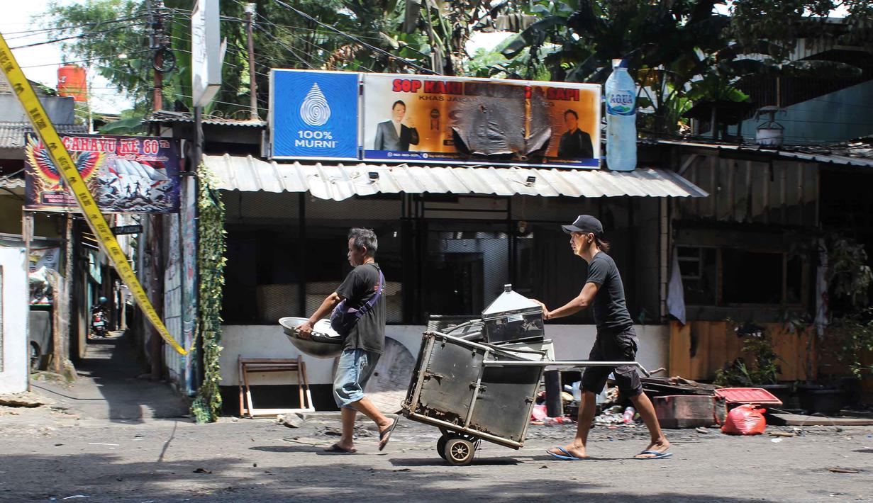 Sebanyak sembilan kios dan delapan kendaraan hangus terbakar. Tampak dalam foto, pemilik kios membersihkan puing-puing bangunan usai kebakaran yang melanda deretan kios di kawasan Kalibata, Jakarta Selatan, pada Jumat (12/12/2025). (merdeka.com/magang/Rendi Saputra)