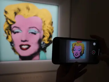 Jurnalis mengambil foto lukisan "Shot Sage Blue Marilyn" karya Andy Warhol selama pratinjau pers di New York, Senin (21/3/2022).  Rumah lelang Christie menyatakan akan melelang lukisan potret Marilyn Monroe yang dibuat Warhol pada 1964 tersebut pada Mei mendatang di New York. (TIMOTHY A. CLARY/AFP)