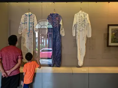 Dua orang melihat hazmat yang ditandatangani dan disumbangkan oleh tim medis dari Guangdong dan Hainan saat mendukung Provinsi Hubei selama lockdown COVID-19 di ruang Pameran Revolusi Wuhan, Wuhan, China, 5 Agustus 2020. (Photo by Hector RETAMAL/AFP)