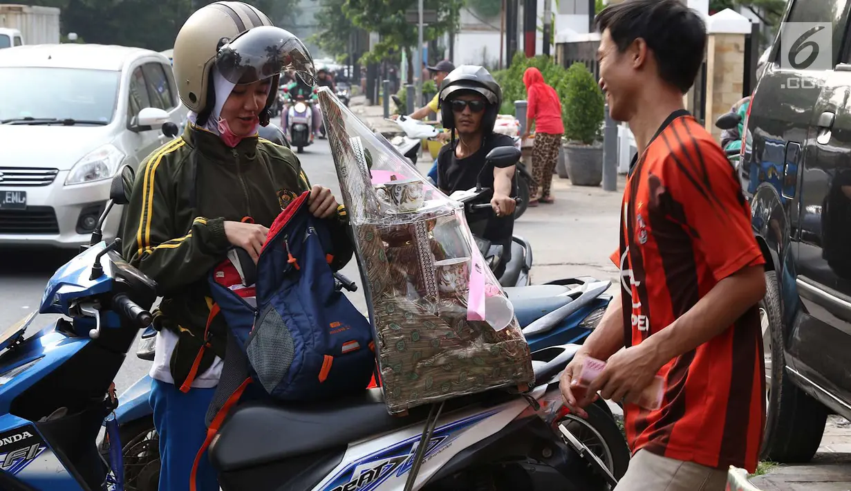 Pedagang menaikkan parsel dagangannya ke sepeda motor pembeli di kawasan Cikini, Jakarta, Rabu (6/6). Menjelang Hari Raya Idul Fitri, penjualan parsel para pedagang dadakan tersebut meningkat hingga 50 persen. (Liputan6.com/Immanuel Antonius)