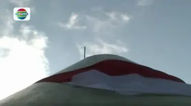 Upaya menaikkan bendera raksasa ini sedikit terkendala karena tiupan angin kencang.