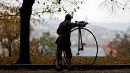 Seorang peserta mengenakan kostum sejarah mendorong sepeda penny farthing sebelum balapan penny farthing tahunan dimulai di Praha, Republik Ceko (5/11). (Reuters/David W Cerny)