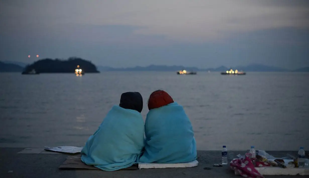 Keluarga korban tenggelamnya kapal ferry Sewol tampak duduk di tepi pantai menanti kepastian kabar keluarganya yang ikut tenggelam 4 hari lalu (AFP Photo/ED Jones)