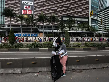Seorang wanita dikenakan sanksi memunguti sampah arena di car free day (CFD) Bundaran HI, Jakarta, Minggu (29/1). Sejumlah pengunjung terjaring operasi tangkap tangan (OTT) karena membuang sampah sembarang di arena CFD. (Liputan6.com/Faizal Fanani)