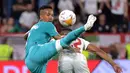 Bek Real Madrid Eder Militao (kiri) berebut bola dengan penyerang Sevilla Anthony Martial  pada lanjutan Liga Spanyol di stadion Ramon Sanchez Pizjuan, Senin (18/4/2022) dini hari WIB. Real Madrid sukses menaklukkan Sevilla 3-2. (CRISTINA QUICLER / AFP)