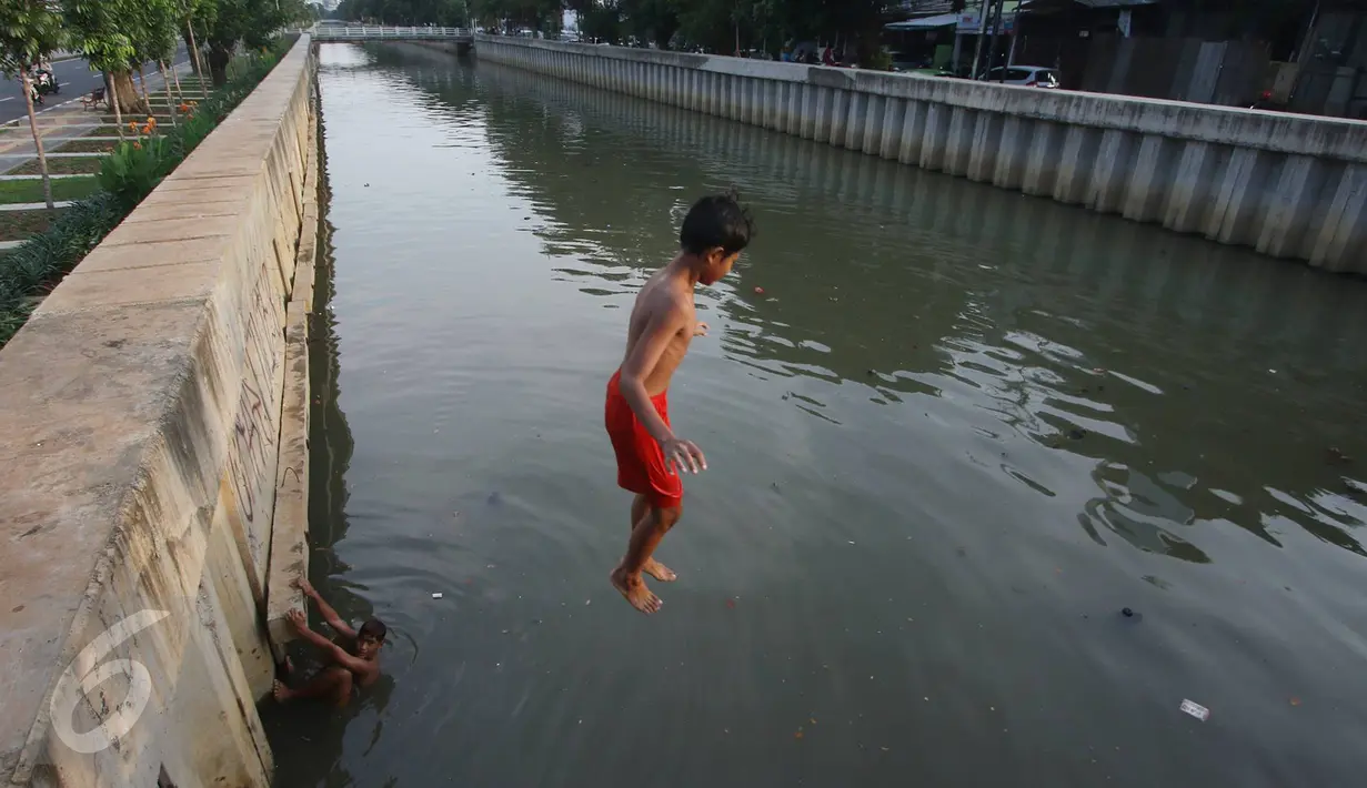 Seorang anak melompat ke anak Kali Ciliwung di Jakarta, Rabu (13/7). Bersihnya kali yang berada di Ibu Kota itu dimanfaatkan anak-anak sekitar untuk berenang sambil mengisi waktu libur sekolah. (Liputan6.com/Immanuel Antonius)