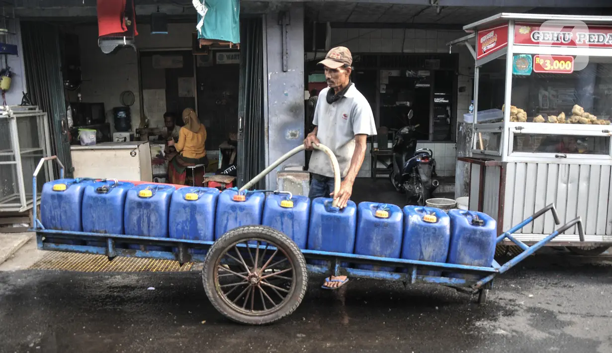 Pedagang mengantarkan air pikulan kepada warga di kampung nelayan Kalibaru, Cilincing, Jakarta Utara, Selasa (22/3/2022). Hingga kini air pikulan masih menjadi kebutuhan utama warga di kawasan pesisir Cilincing untuk keperluan konsumsi akibat air sumur keruh dan bau. (merdeka.com/Iqbal S Nugroho)