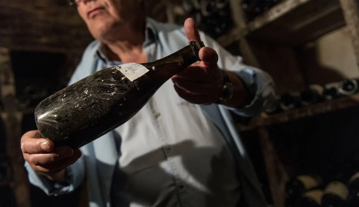 Seorang pria memegang botol anggur "Vin Jaune" tahun 1774 di Arbois, Perancis timur (22/5). Tiga botol anggur produksi tahun 1774 akan dijual pada 26 Mei 2018, selama lelang. (AFP Photo/Sebastian Bozon)