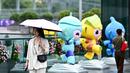 Seorang wanita berjalan melewati maskot Asian Games 2022 (Chenchen, Congcong, dan Lianlian) yang terletak di sepanjang Sungai Qiantang di Hangzhou, Zhejiang, China pada 22 September 2023 waktu setempat. (AFP/Manan Vatsyayana)