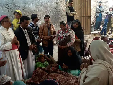 Sejumlah orang meratapi jenazah keluarganya di Toba Tek Singh, sekitar 338 km dari Islamabad, Selasa (27/12). Sedikitnya 24 orang di kalangan kelompok kecil Kristen di Pakistan tewas setelah mengonsumsi minuman keras oplosan saat perayaan Natal. (STR/AFP)