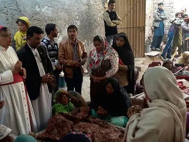 Sejumlah orang meratapi jenazah keluarganya di Toba Tek Singh, sekitar 338 km dari Islamabad, Selasa (27/12). Sedikitnya 24 orang di kalangan kelompok kecil Kristen di Pakistan tewas setelah mengonsumsi minuman keras oplosan saat perayaan Natal. (STR/AFP)