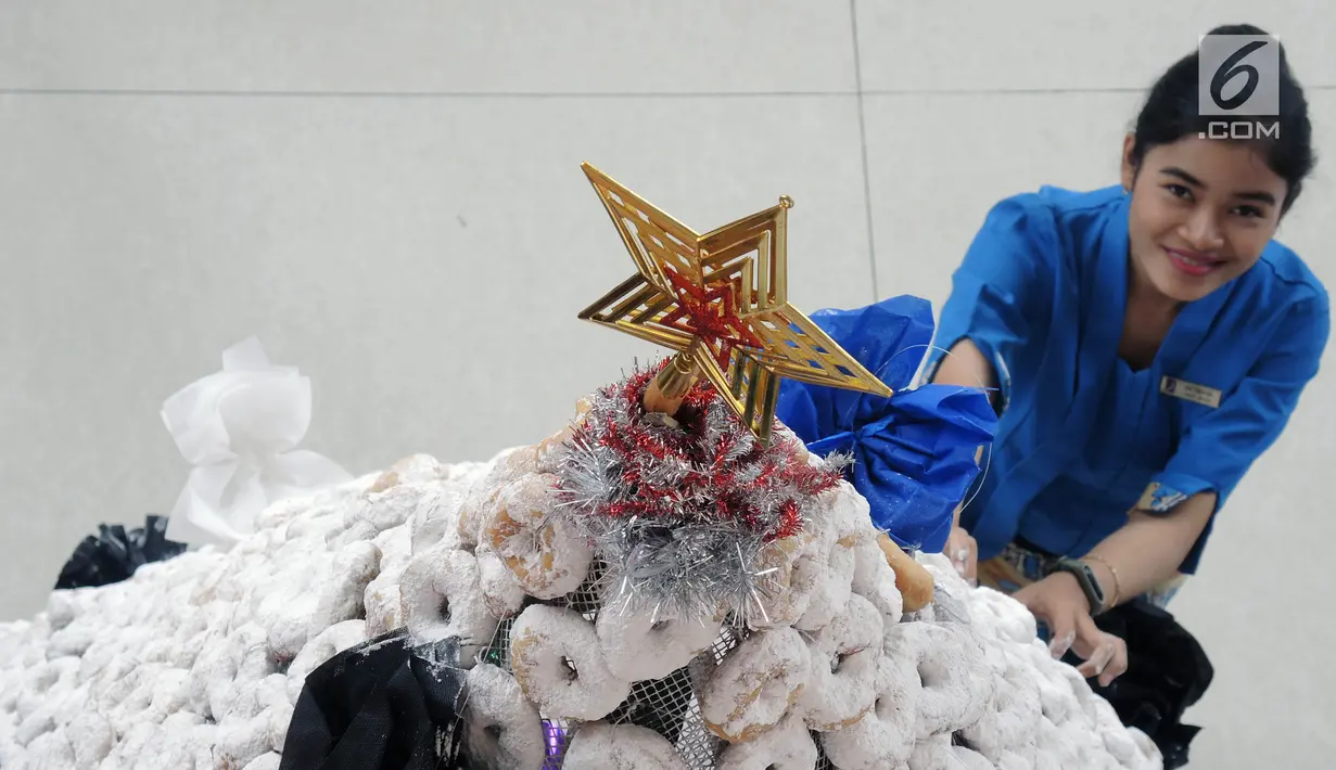 Karyawan membuat pohon Natal dari susunan donat di lobby hotel Dafam Semarang, Rabu (12/12). Pohon Natal setinggi 3 meter untuk menyambut Natal tersebut terdapat 2000 buah kue donat. (Liputan6.com/Gholib)