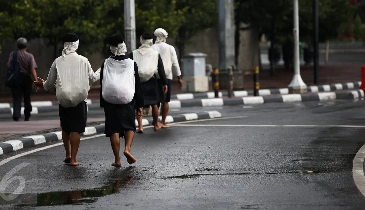 Empat warga Baduy berjalan kaki melintasi kawasan Bundaran HI, Jakarta, Selasa (6/9). Warga Baduy berjalan ratusan kilometer dari kampung mereka tanpa alas kaki dan sama sekali tidak menggunakan kendaraan bermotor. (Liputan6.com/Faizal Fanani)