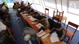 Murid SMP dan SMA Sekolah Khusus (SKh) Assalam 01 melaksanakan ujian di tenda darurat halaman SKh Assalam 02, Ciater, Serpong, Tangerang Selatan, Selasa (3/12/2019). Mereka terpaksa melaksanakan ujian dalam tenda lantaran gedung sekolahnya ambruk akibat pergerakan tanah. (merdeka.com/Arie Basuki)