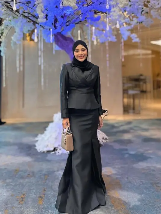 Sementara itu Aurel Hermansyah menunjukan tubuh yang kini langsing. Ia memilih mengenakan atasan blazer hitam serasi dengan kerudung dan rok polos model mermaid. Ia membawa tas Dior di tangannya.  [@aurelhermansyaah]