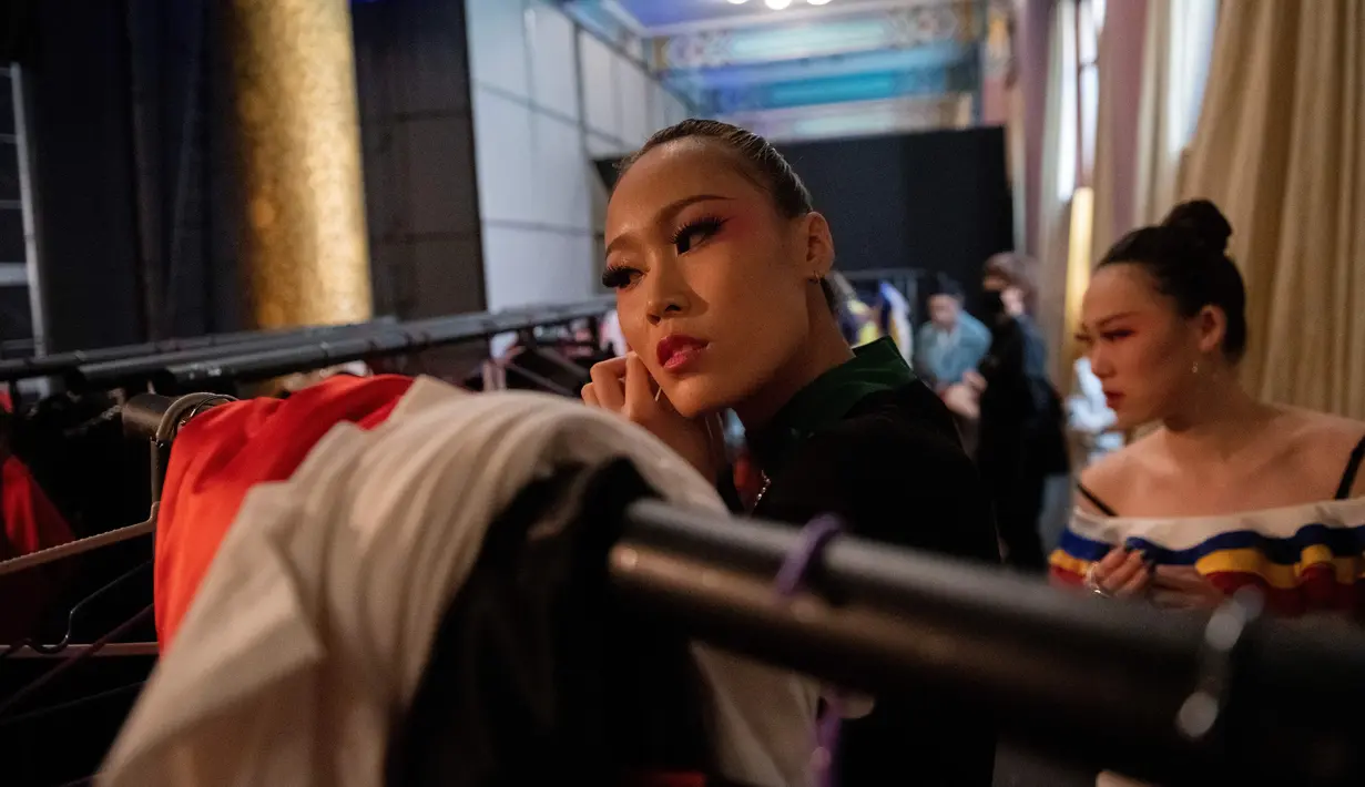 Seorang model memakai anting di belakang panggung sebelum memamerkan koleksi oleh Zhang Kejia selama China Fashion Week di Beijing (26/3). (AFP Photo/Nicolas Asfouri)