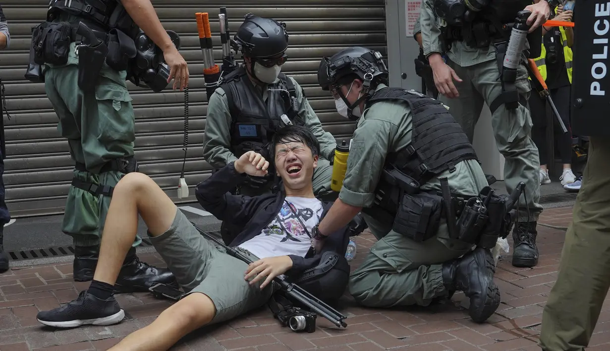 Seorang wartawan jatuh setelah disemprot dengan semprotan merica oleh polisi dalam unjuk rasa menentang Undang-Undang Keamanan Nasional pada hari peringatan penyerahan Hong Kong ke China dari Inggris di Hong Kong, Rabu (1/7/2020). (AP Photo/Vincent Yu)