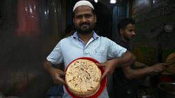 Pemilik toko memajang roti Sheermal untuk dijual di pasar pada hari pertama bulan suci Ramadhan di kawasan tua Delhi, India, 3 April 2022. Masjid dan jalan-jalan pasar penuh dengan keramaian malam, tergoda oleh aroma manisan manis untuk berbuka puasa. (Money SHARMA/AFP)