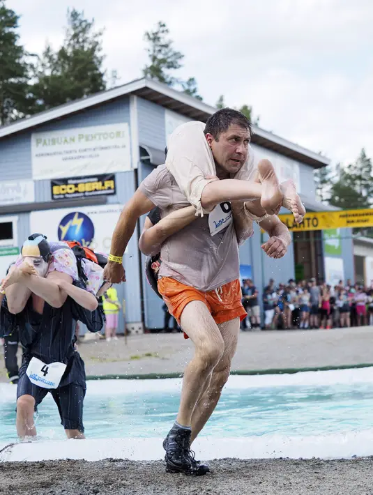 Iana Bessolitcyna dan Georgii Kostiukov dari Rusia (tengah) serta Sayaka dan Eisuke Kawahara dari Jepang (kiri) bersaing selama kompetisi Wife Carrying World Championships di Sonkajarvi, Finlandia, 2 Juli 2016. (Timo Hartikainen/Lehtikuva/AFP)