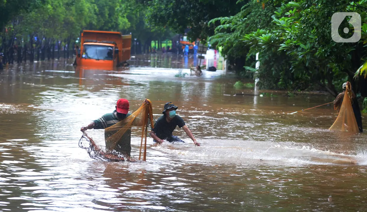 Warga menjala ikan di tengah jalan yang tertutup banjir di kawasan TB Simatupang, Jakarta Selatan, Sabtu (20/2/2021). Banjir terjadi akibat luapan Kali Serua yang berada di pinggir jalan tol. (merdeka.com/Arie Basuki)