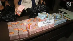 Petugas BNN menunjukkan barang bukti uang hasil TPPU di Kantor BNN, Jakarta, Selasa (17/7). BNN menyita uang dari dua rekening dan satu unit rumah dengan total aset sebesar Rp 3,9 miliar. (Liputan6.com/Arya Manggala)