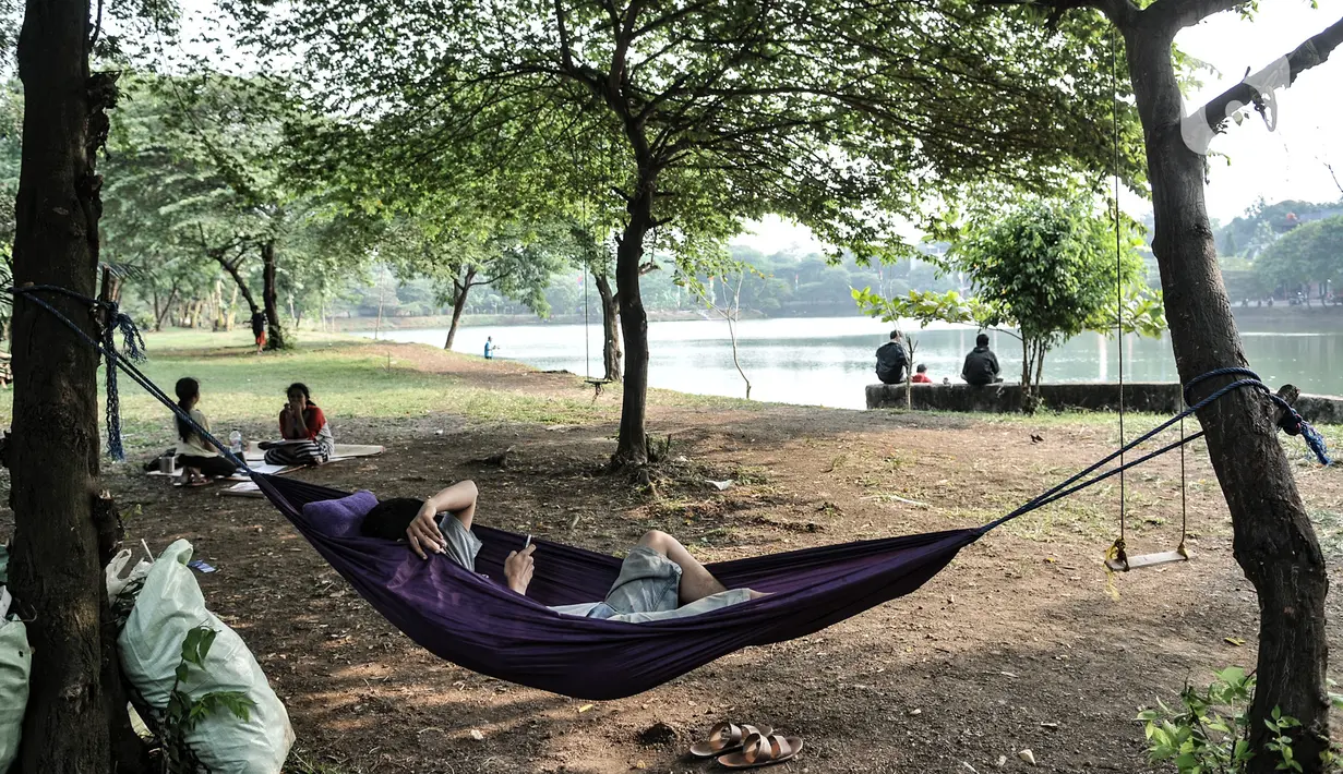 Warga saat bersantai di pinggir Waduk Setu, Cipayung, Jakarta, Selasa (28/7/2020). Pemerintah Kota (Pemkot) Jakarta Timur akan menjadikan Waduk Setu sebagai pusat ekowisata yang ditargetkan terwujud pada Oktober mendatang. (merdeka.com/Iqbal S. Nugroho)