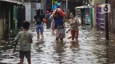 Warga melintasi banjir di salah satu permukiman penduduk di Kawasan Cengkareng Barat, Jakarta Barat, Kamis (30/1/2025). (Liputan6.com/Angga Yuniar)