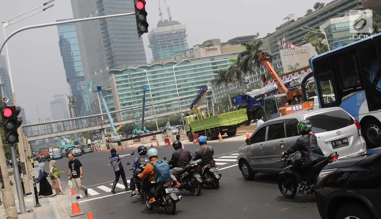Petugas mengatur lalu lintas di pelican crossing di kawasan Thamrin, Jakarta, Minggu (29/7). Pelican crossing di kawasan Thamrin sudah bisa di gunakan pengganti JPO yang akan dibongkar. (Liputan6.com/Herman Zakharia)