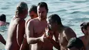 Seorang pria mencium sebuah salib kayu yang dilemparkan ke dalam air oleh seorang imam, di lepas pantai pinggiran pesisir Athena selama Hari Epiphany Orthodox, Yunani (6/1). (AFP Photo/Louisa Gouliamaki)