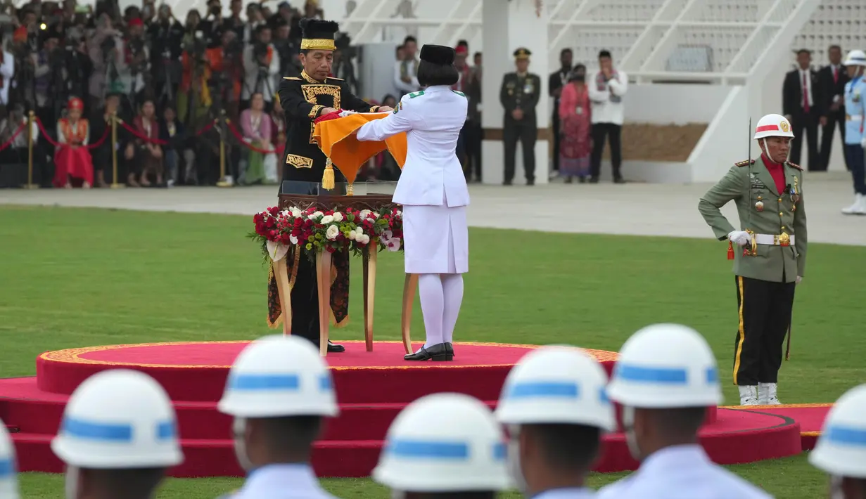 Presiden Joko Widodo (kiri tengah) menyerahkan bendera Merah-Putih kepada seorang pembawa bendera untuk dikibarkan dalam upacara Peringatan Kemerdekaan ke-79 Republik Indonesia di Istana Kepresidenan yang baru di Ibu Kota Negara, Nusantara, Sabtu, 17 Agustus 2024. (AP Photo/Achmad Ibrahim)