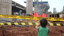 Seorang anak melihat kondisi tiang girder Tol Bekasi-Cawang-Kampung Melayu (Becakayu) yang ambruk di Kebon Nanas, Jakarta Timur, Selasa (20/2). Peristiwa terjadi saat para pekerja melakukan pengecoran pada penyangga tiang. (Liputan6.com/Arya Manggala)
