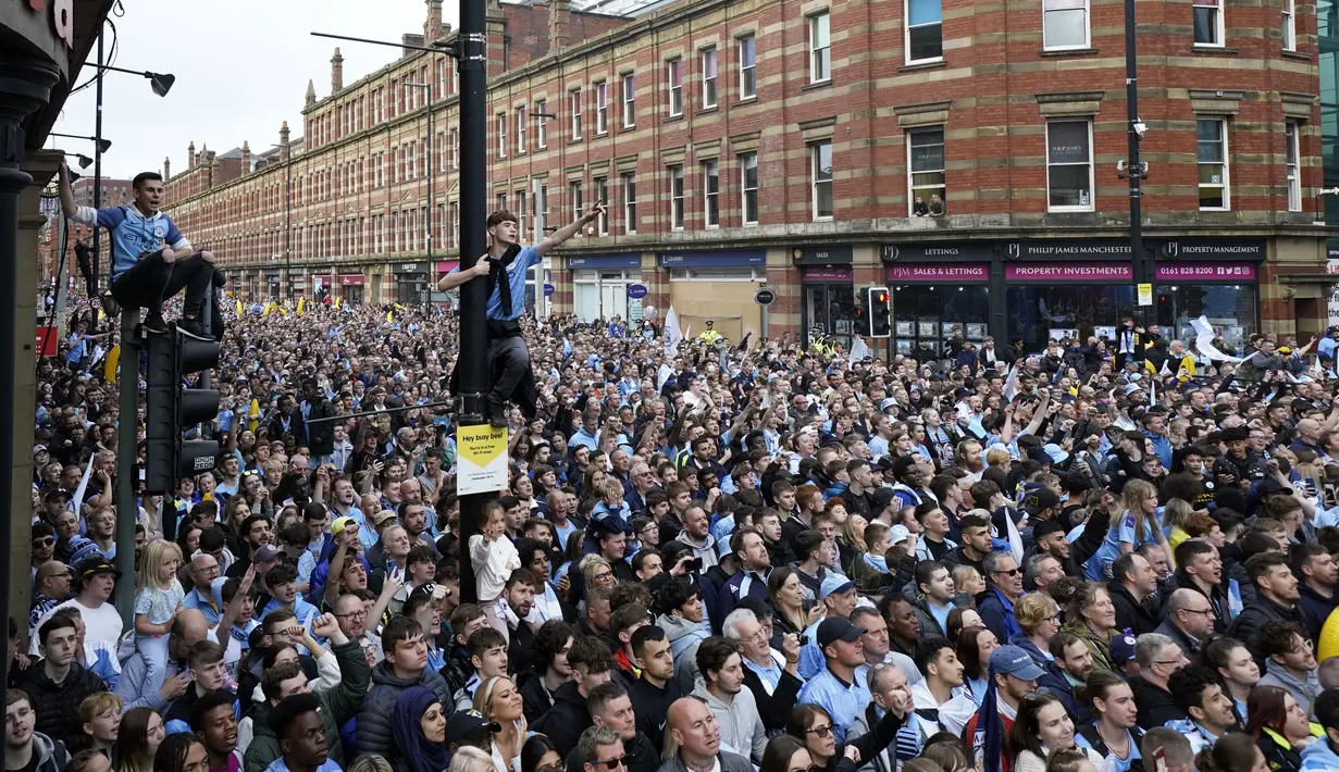 Fans berkumpul untuk menyaksikan parade kemenangan Manchester City dalam Liga Inggris di Manchester, Inggris, 23 Mei 2022. (AP Photo/Jon Super)