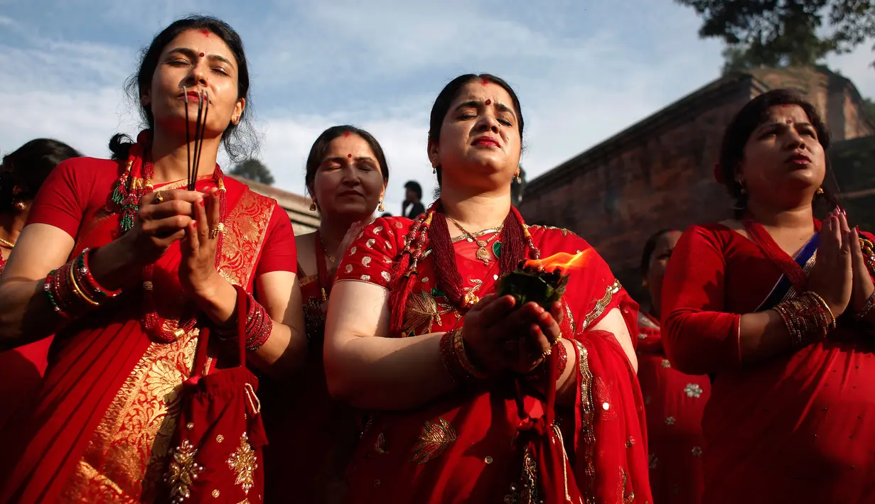 Para wanita Nepal berdoa saat festival Teej di Kathmandu, Nepal, Kamis (24/8). Warna merah dalam festival ini diambil dari makna kata ‘Teej’ yang berarti serangga merah kecil yang keluar dari tanah saat musim hujan. (Niranjan Shrestha/AP)