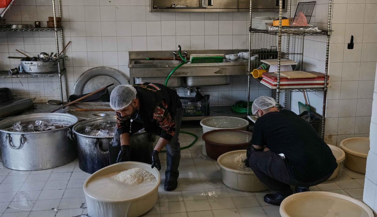 Sejumlah keluarga mengungsi di Institut Teknik Bir Hassan yang telah diubah menjadi tempat penampungan. Tampak dalam foto, para sukarelawan memasak makanan untuk para pengungsi yang menghindari serangan udara Israel di Lebanon selatan dan Dahiyeh, di Institut Teknik Bir Hassan yang telah diubah menjadi tempat penampungan, Beirut, Rabu 11 Maret 2026. (AP Photo/Bilal Hussein)