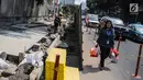 Warga melintas di samping proyek revitaslisasi trotoar di kawasan Cikini, Jakarta, Senin (1/7/2019). Revitalisasi trotoar di kawasan Cikini hingga Kramat ditargetkan rampung pada Desember 2019. (Liputan6.com/Faizal Fanani)