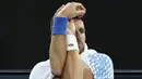 Petenis Serbia, Novak Djokovic melakukan peregangan saat melawan petenis Prancis, Enzo Couacaud pada Australian Open 2023 di Melbourne, Australia, 19 Januari 2023. (AFP/Martin Keep)