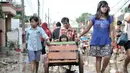 Seorang anak didorong menggunakan gerobak usai banjir menerjang Perumahan Pondok Gede Permai, Jatiasih, Bekasi, Jawa Barat, Kamis (2/1/2020). Terjangan banjir setinggi lima meter tersebut menyisakan lumpur dan sampah yang memenuhi seluruh kompleks perumahan. (merdeka.com/Iqbal Nugroho)