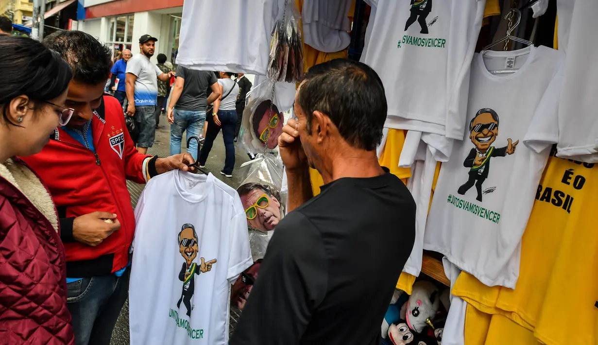 Pembeli memilih kaus bergambar Calon Presiden Brasil, Jair Bolsonaro dari sayap kanan dijajakan di sebuah toko pinggir jalan yang populer di Sao Paulo, 8 Oktober 2018. Bolsonaro unggul dalam penghitungan suara pemilu putaran pertama. (AFP/NELSON ALMEIDA)