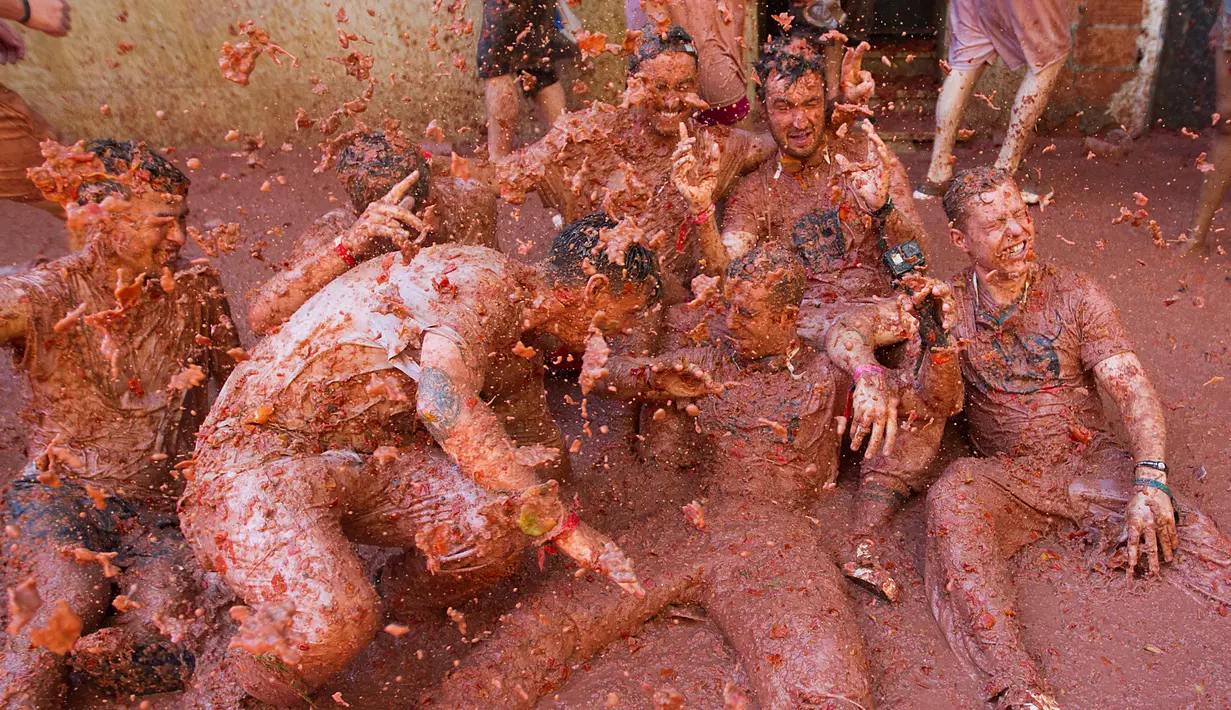 Peserta bersuka ria dengan tomat yang hancur saat festival tahunan "Tomatina" di Bunol, salah satu kota di timur Spanyol, Rabu (29/8/2019). Digelar sejak 1945, perang tomat ini menjadi daya tarik utama bagi wisatawan mancanegara seperti dari Inggris, Jepang, dan AS. (JAIME REINA / AFP)