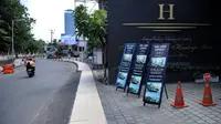 Papan nama promosi terlihat di luar hotel di jalan utama yang sepi saat Pemberlakuan Pembatasan Kegiatan Masyarakat (PPKM) Level 3 di Kuta, Badung, Bali, Jumat (23/7/2021). Selama PPKM Level 3 di Bali, tempat usaha boleh buka hingga pukul 21.00 Wita. (SONNY TUMBELAKA/AFP)