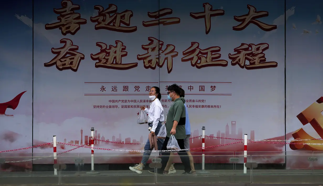 Orang-orang yang memakai masker berjalan di dekat papan stiker dengan berbagai gedung pencakar langit kota di sebuah gedung perkantoran yang mengalami kontraksi di Beijing, Rabu, 17 Agustus 2022. Pabrik-pabrik di barat daya China telah ditutup dan sebuah kota memberlakukan pemadaman bergilir setelah waduk yang digunakan untuk menghasilkan tenaga air mulai menipis akibat kekeringan yang memburuk. (AP Photo/Andy Wong)
