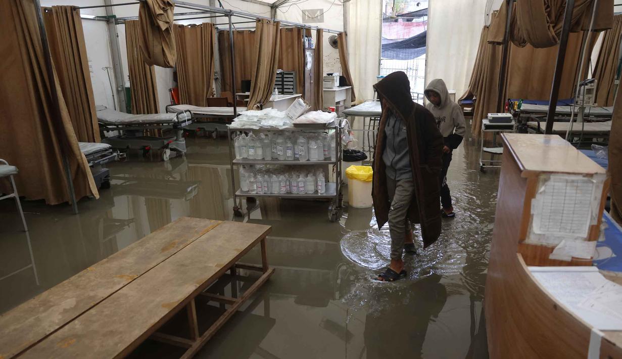 Selain tenda darurat milik Rumah Sakit Nasser, hujan deras yang mengguyur Khan Yunis, Gaza Selatan, pada Kamis 26 Maret 2026, juga merendam tenda-tenda pengungsi. Tampak dalam foto, genangan air menutupi lantai tenda darurat milik Rumah Sakit Nasser, yang berfungsi sebagai tempat penerimaan pasien rawat jalan dan departemen gawat darurat, setelah hujan lebat di Khan Yunis di Jalur Gaza selatan pada 26 Maret 2026. (Bashar Taleb/AFP)