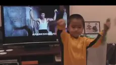 Dengan baju kuning berstrip hitam, bocah kecil memainkan dobel stik bergaya ala Bruce Lee. Hebatnya, si bocah memainkan alat yang seharusnya dimainkan orang dewasa ini dengan mahir