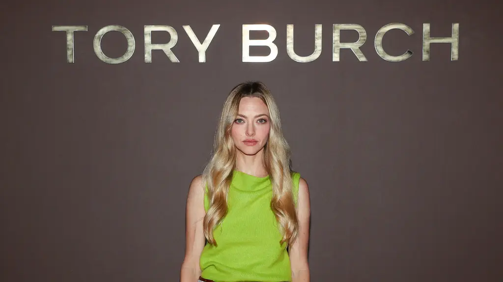 Amanda Seyfried hadir dengan koleksi Resort 2027. Padanan brushed wool top, patent leather skirt, woven raffia belt, dengan the suede Bunny Knot shoulder bag, dan peep-toe pumps. / Foto: Tory Burch.