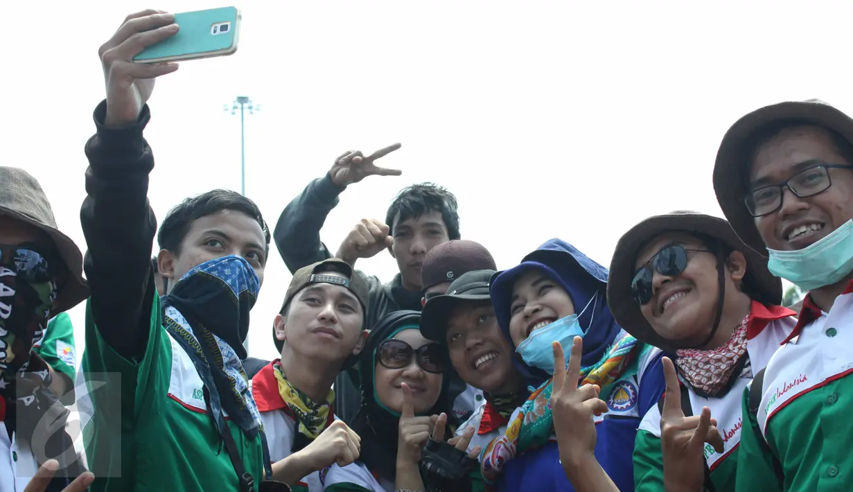 Para buruh berselfie disela aksi  unjuk rasa di kawasan Patung Kuda, Jakarta, Selasa (1/8/2015). Mereka menuntut pemerintah menghentikan gelombang PHK yang mengancam akibat melemahnya nilai tukar rupiah terhadap dolar. (Liputan6.com/Gempur M Surya)