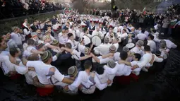 Para pria bernyanyi dan menari saat merayakan Epiphany di Sungai Tundzha, Kalofer, Bulgaria, 6 Januari 2022. Epiphany adalah sebuah hari raya keagamaan dalam sejumlah denominasi gereja Kristen pada tanggal 6 Januari. (AP Photo/Valentina Petrova)